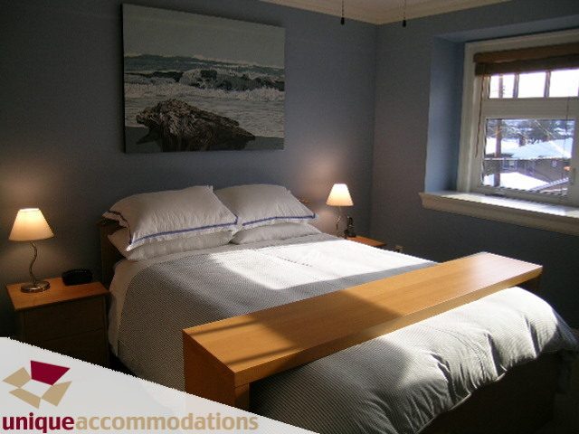 Spacious bedroom with ocean painting, wooden headboard, and window view. - 3030 West 15th Avenue, Vancouver West Side