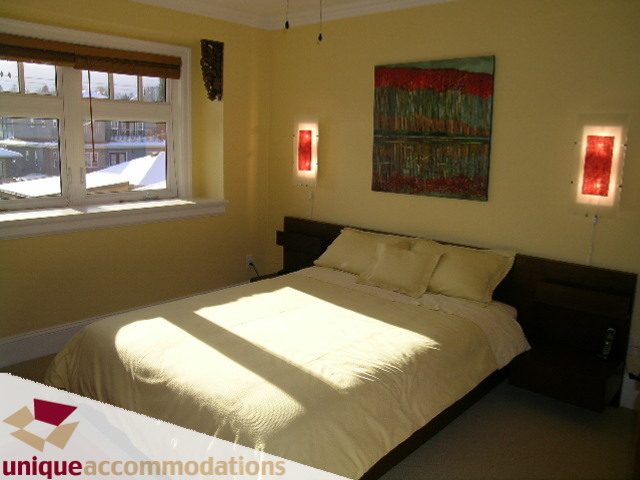 Bright bedroom with two queen beds, yellow walls, and a large window with a city view. - 3030 West 15th Avenue, Vancouver West Side