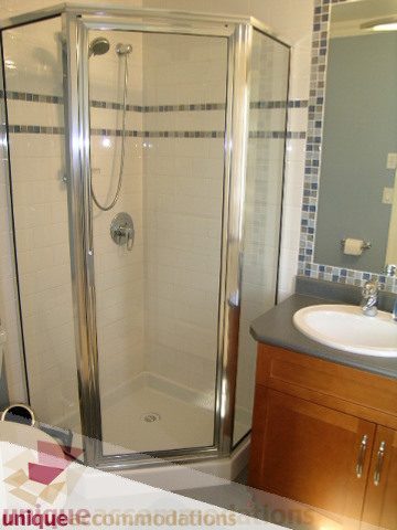 Bathroom with modern shower, wooden vanity, and gray countertop. - 3030 West 15th Avenue, Vancouver West Side