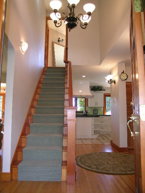 Open-concept living with hardwood floors, modern kitchen, and a cozy staircase leading to upper levels. - 2148 Kings Ave, West Vancouver