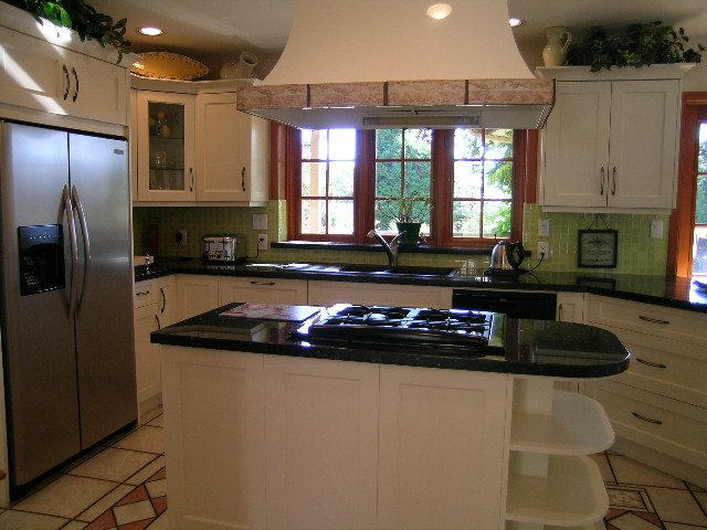 Bright kitchen with black countertops, white cabinets, and a large bay window. - 2148 Kings Ave, West Vancouver