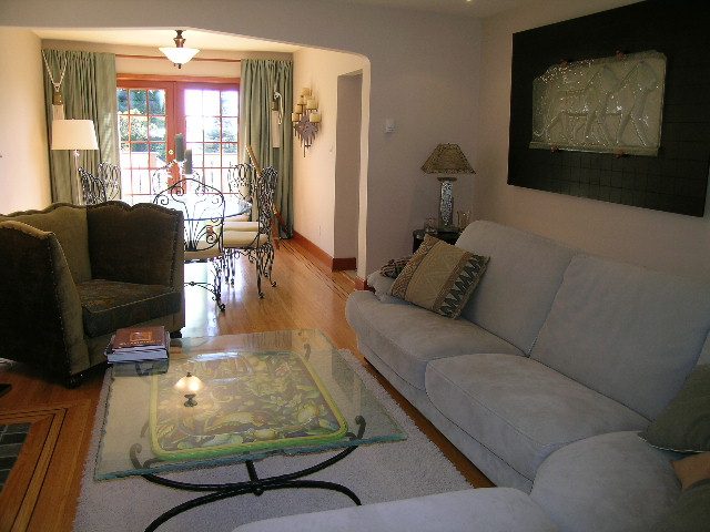 Spacious living room with light blue couch, wooden floors, and a view of the garden outside. - 2148 Kings Ave, West Vancouver