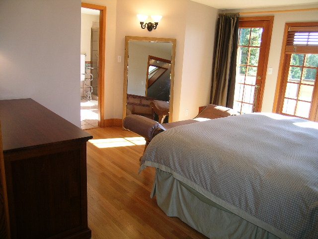 Bright bedroom with hardwood floors, large windows, and a cozy bed setup. - 2148 Kings Ave, West Vancouver