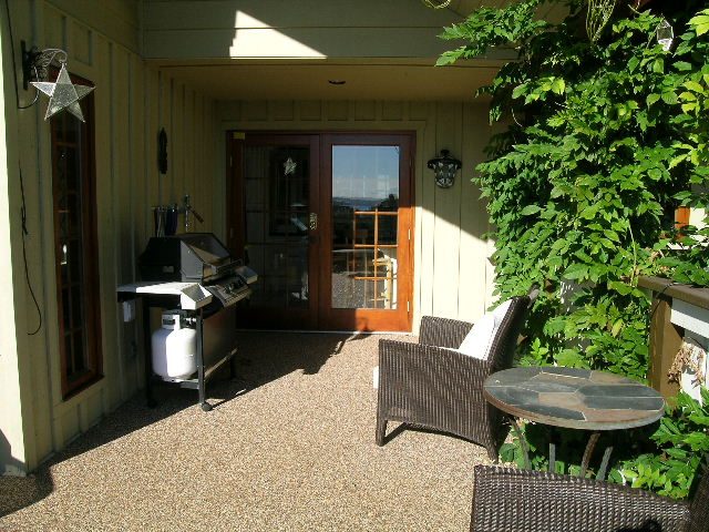 Outdoor patio with a barbecue grill, wooden door, and greenery. - 2148 Kings Ave, West Vancouver