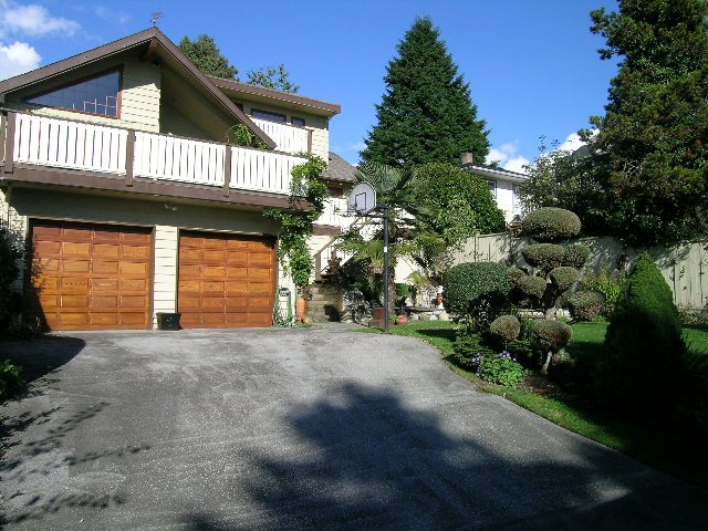 Bright house with wooden garage doors and well-maintained topiary garden. - 2148 Kings Ave, West Vancouver