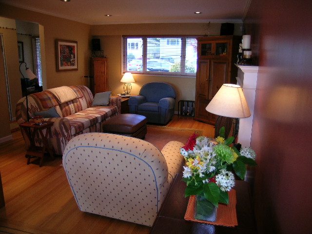 Spacious living room with hardwood floors, cozy sofa, and floral centerpiece. - 875 Whitchurch Street, North Vancouver