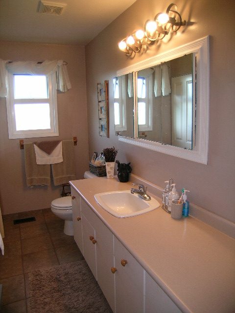 Spacious bathroom with dual sinks, large mirror, and natural light from window. - 875 Whitchurch Street, North Vancouver