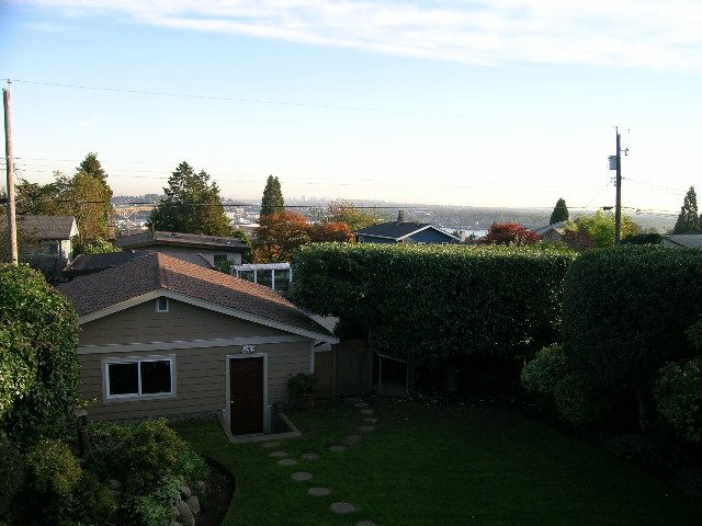 Backyard with neatly trimmed hedges and a city view in the distance. - 875 Whitchurch Street, North Vancouver