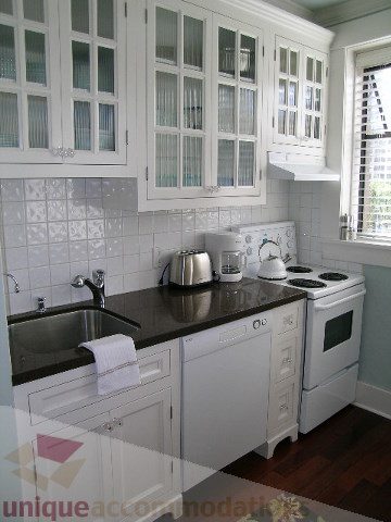 Bright kitchen with white cabinets, black countertops, and hardwood floors. - 45 - 777 Burrard Street, Vancouver Downtown