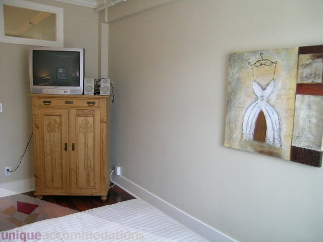 Bright bedroom with wooden cabinet, small TV, and wall art featuring a dress. - 45 - 777 Burrard Street, Vancouver Downtown