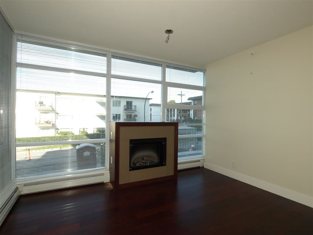 Bright living room with hardwood floors, city view, and a modern fireplace. - 104 - 1320 Chesterfield, North Vancouver