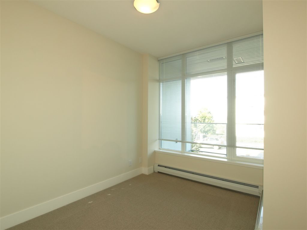 Bright living room with large windows and carpeted floor. - 104 - 1320 Chesterfield, North Vancouver