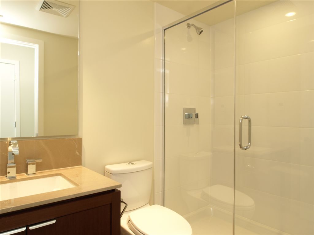 Bright bathroom with modern sink, toilet, and glass shower enclosure. - 104 - 1320 Chesterfield, North Vancouver