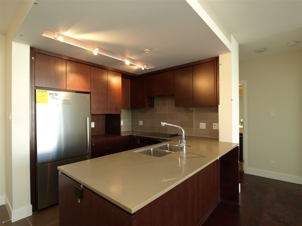 Bright kitchen with modern cabinetry, granite countertops, and hardwood floors. - 104 - 1320 Chesterfield, North Vancouver