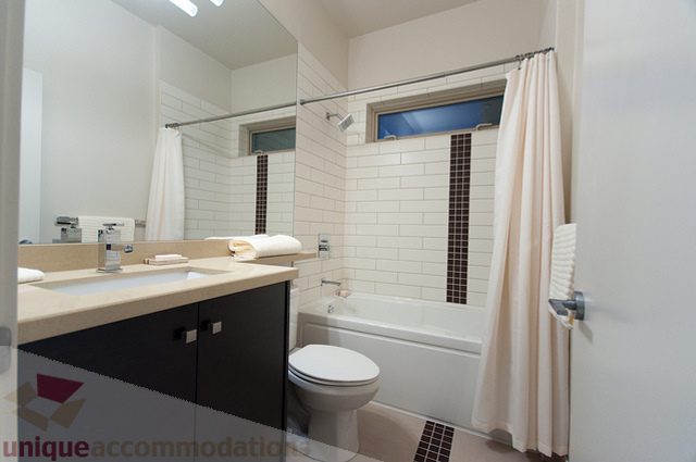 Furnished bathroom with white subway tiles, countertop, and shower curtain. - 1381 Bute Street, Vancouver Downtown