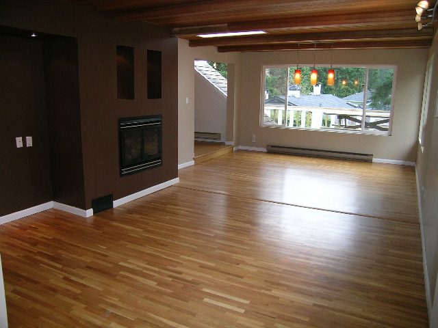 Spacious living room with hardwood floors, large windows, and a cozy fireplace. - 43 Glenmore Drive, West Vancouver