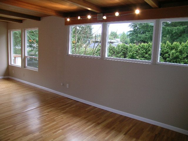 Spacious living room with hardwood floors and large windows offering a serene view of lush greenery. - 43 Glenmore Drive, West Vancouver