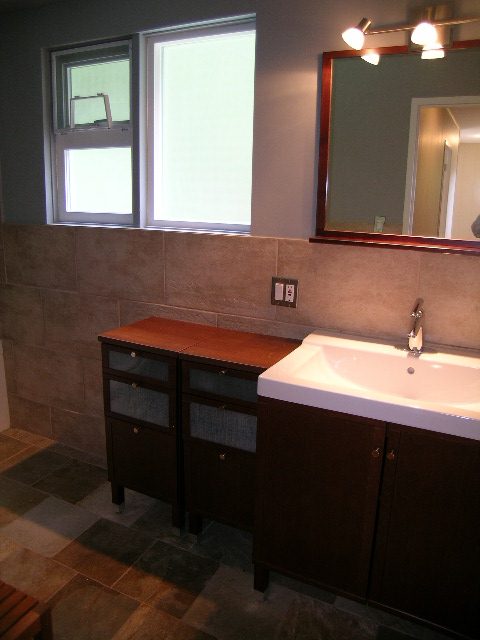 Bathroom with dark wood cabinets, white sink, and large mirror. - 43 Glenmore Drive, West Vancouver