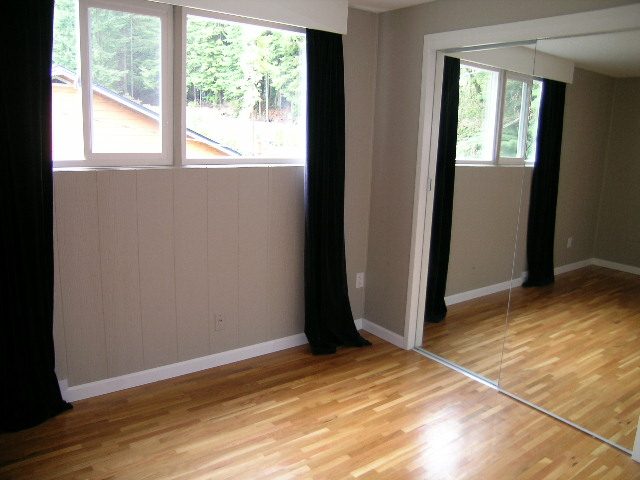 Spacious bedroom with hardwood floors and large windows, offering a serene forest view. - 43 Glenmore Drive, West Vancouver