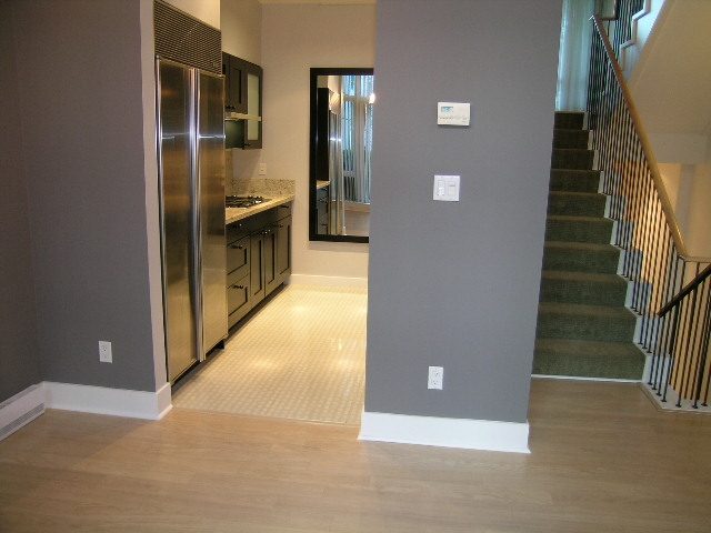 Modern kitchen with stainless steel appliances and hardwood floors, leading to a staircase. - 1455 West Hastings, Vancouver Downtown