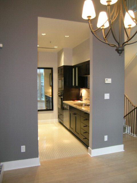 Open-concept kitchen with dark cabinets, white countertops, and hardwood floors. - 1455 West Hastings, Vancouver Downtown
