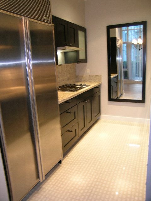 Modern kitchen with stainless steel appliances and granite countertops, featuring a city view through a large mirror.