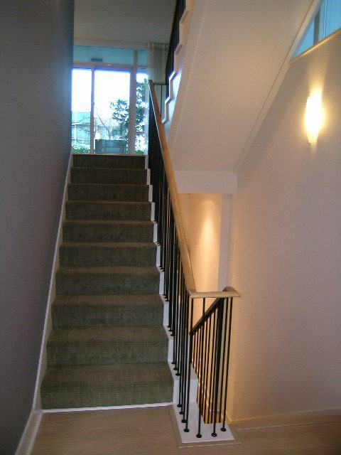 Staircase leading to second floor with carpeted steps and modern railings, showcasing a clean and inviting interior.