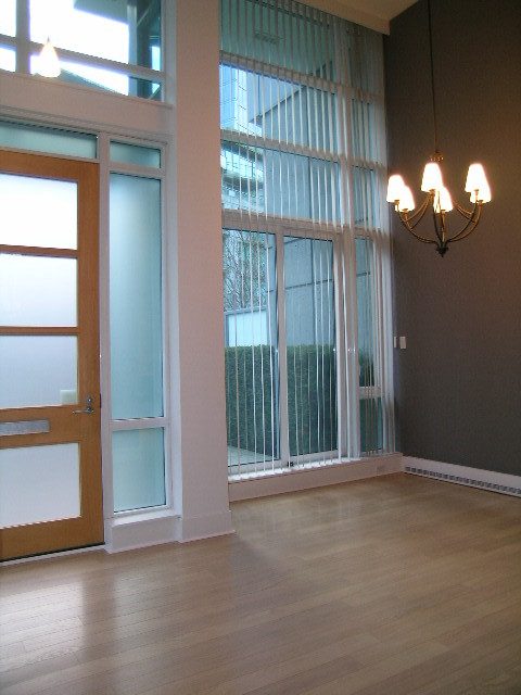 Spacious living room with hardwood floors, large windows, and a chandelier. - 1455 West Hastings, Vancouver Downtown
