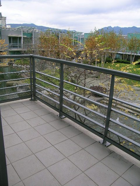 Balcony with tiled flooring and metal railings, offering a view of the city and greenery. - 1455 West Hastings, Vancouver Downtown