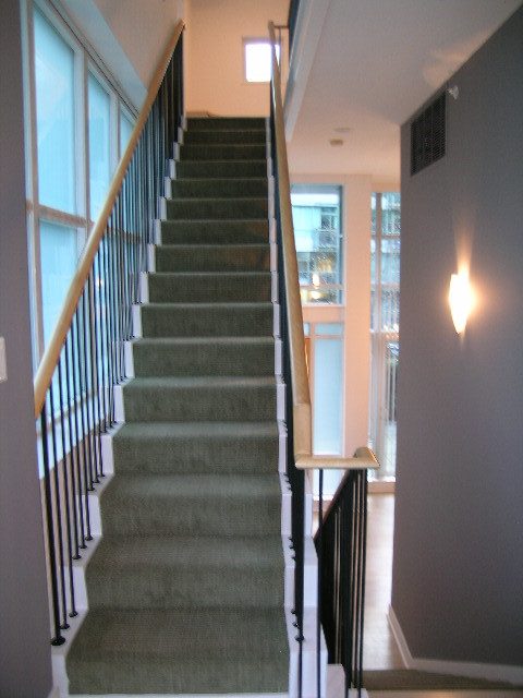Staircase leading to upper level with carpeted steps and wooden railings, showcasing a clean and modern design.
