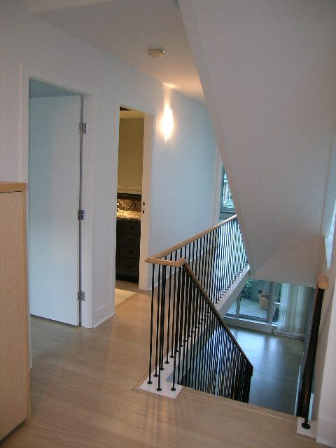 Open-concept living area with hardwood floors, modern railings, and a glimpse of the kitchen in the background.