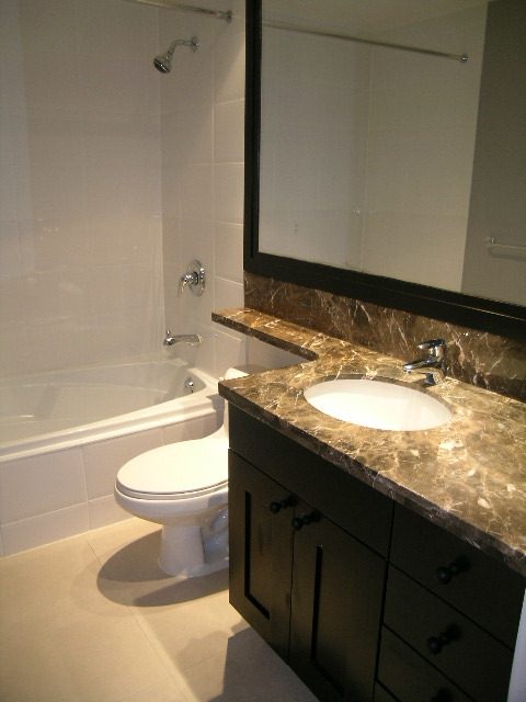 Modern bathroom with marble countertops and a large vanity mirror. - 1455 West Hastings, Vancouver Downtown