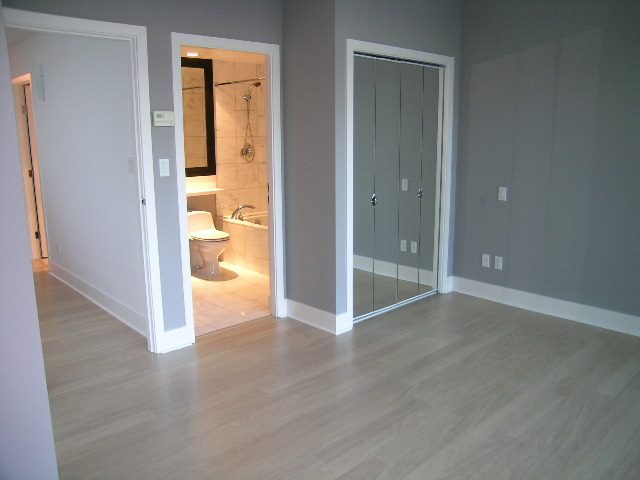 Spacious living room with hardwood floors and a view into the bathroom, showcasing a modern design. - 1455 West Hastings, Vancouver Downtown