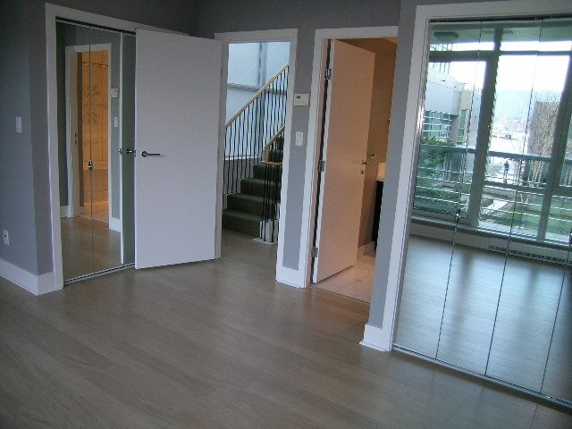 Spacious open-concept living room with hardwood floors, leading to a balcony with city views. - 1455 West Hastings, Vancouver Downtown