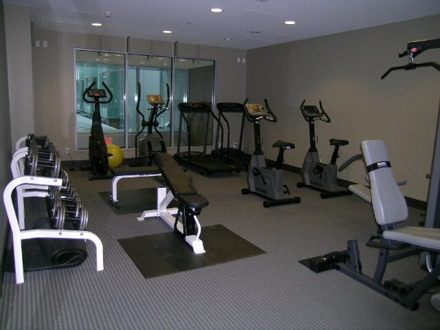 Spacious fitness room with cardio equipment and mirrors, perfect for workouts. - 1455 West Hastings, Vancouver Downtown