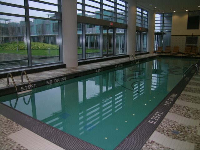 Spacious living room with large windows and a modern indoor pool area. - 1455 West Hastings, Vancouver Downtown