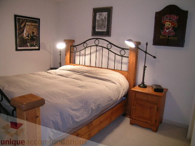 Spacious bedroom with a cozy bed, wooden headboard, and desk lamp, perfect for a comfortable stay. - 215 - 3727 West 10th Avenue, Vancouver West Side