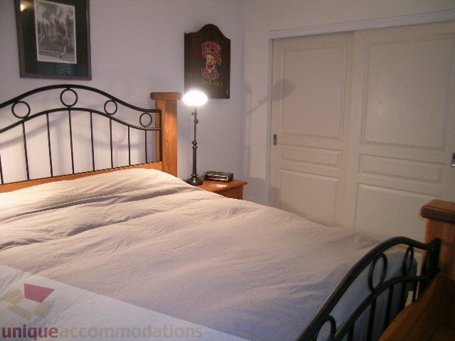 Spacious bedroom with iron bed frame, white bedding, and wooden nightstand. - 215 - 3727 West 10th Avenue, Vancouver West Side