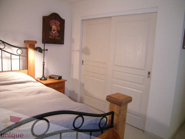 Spacious bedroom with wooden headboard, sliding closet doors, and a cozy corner desk setup. - 215 - 3727 West 10th Avenue, Vancouver West Side