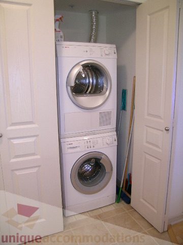 Spacious laundry room with white cabinets, a washer, dryer, and vent hose. - 215 - 3727 West 10th Avenue, Vancouver West Side