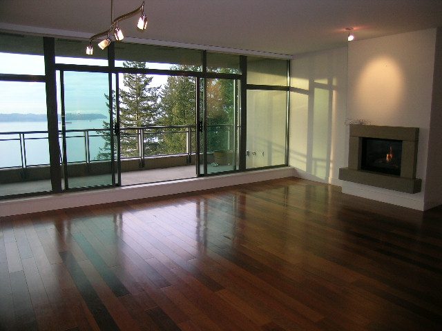 Spacious living room with hardwood floors, large windows, and a view of the water. - 602 - 3355 Cypress Place, West Vancouver