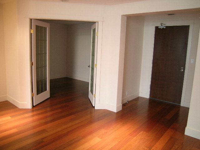 Bright living room with hardwood floors and a dark wooden door. - 602 - 3355 Cypress Place, West Vancouver