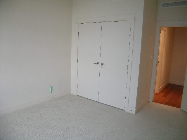 Bright bedroom with white closet doors and carpeted floor. - 602 - 3355 Cypress Place, West Vancouver