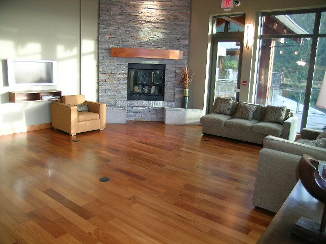 Furnished living room with hardwood floors, stone fireplace, and large windows. - 602 - 3355 Cypress Place, West Vancouver