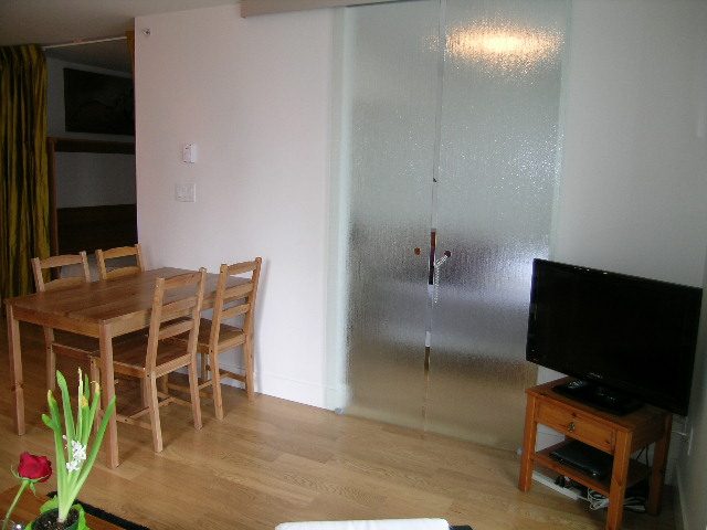 Spacious living room with hardwood floors, a dining area, and a flat-screen TV on a wooden stand. - 608 - 565 Smithe Street, Vancouver Downtown