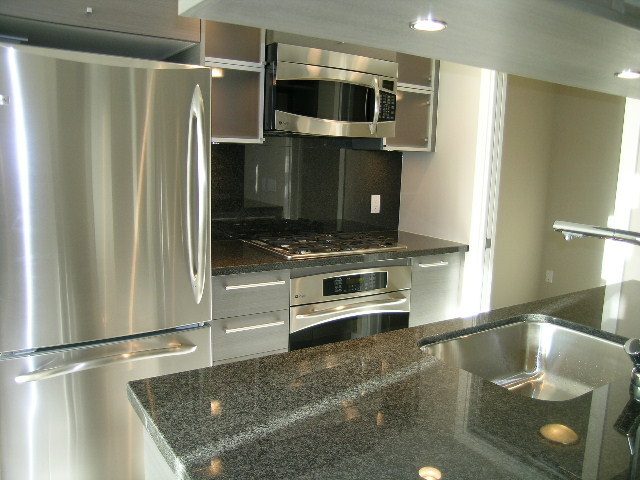 Modern kitchen with granite countertops and stainless steel appliances. - 2307 - 833 Seymour Street, Vancouver Downtown
