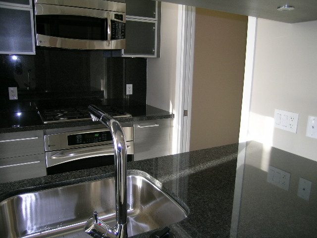 Bright kitchen with granite countertops and stainless steel appliances, showcasing a modern and clean design.