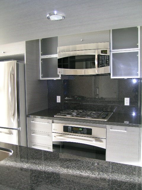 Modern kitchen with sleek black countertops and stainless steel appliances, perfect for a cozy downtown condo.