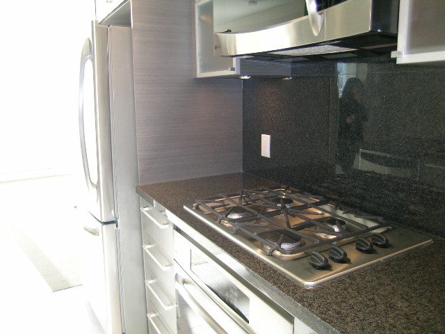Modern kitchen with granite countertops and stainless steel appliances, perfect for a cozy downtown condo.