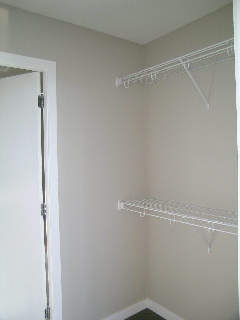 Spacious walk-in closet with white shelving and hooks, perfect for storage. - 2307 - 833 Seymour Street, Vancouver Downtown